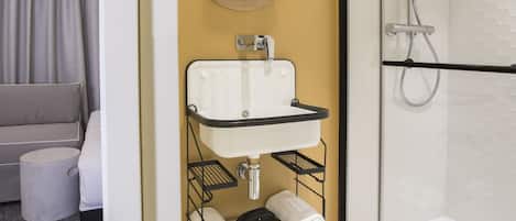 Een moderne badkamer met een douchecabine van glas, een witte wastafel met spiegel en een handdoekhouder.
