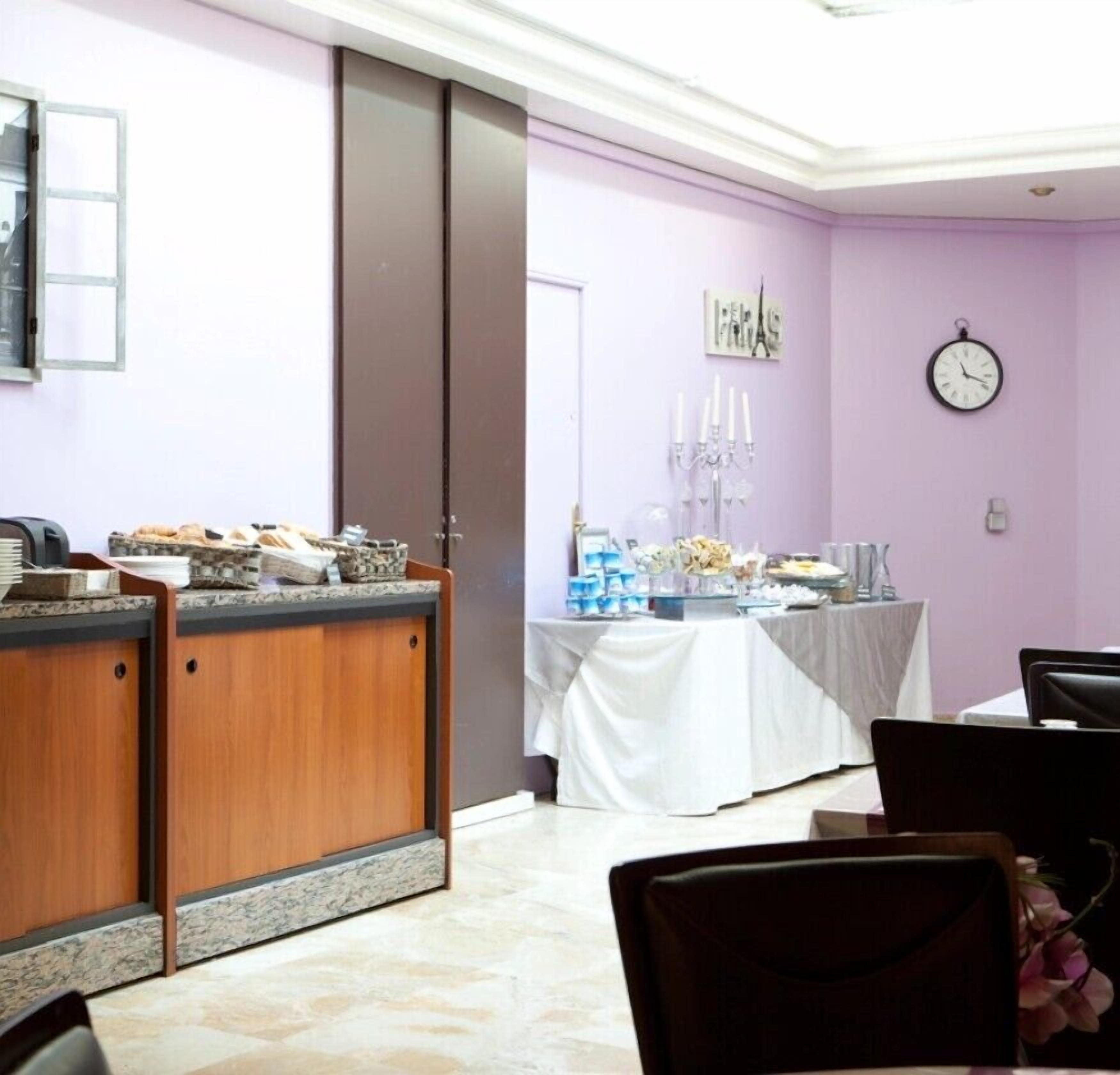 Una habitación con mostrador de recepción, una mesa con mantel blanco y un reloj en la pared.