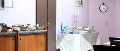 Una habitación con mostrador de recepción, una mesa con mantel blanco y un reloj en la pared.