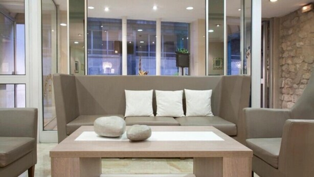 A modern living room with a sofa, two armchairs, and a coffee table. - Hôtel Lebron (Paris)