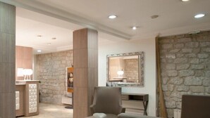 A modern lobby with a stone wall, a reception desk, and comfortable seating areas. - Hôtel Lebron (Paris)