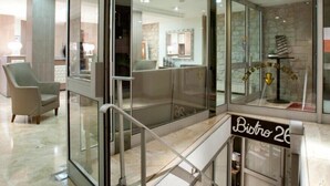 A modern hotel lobby with a glass partition, a sign for 'Bistro 26', and a view of the kitchen area. - Hôtel Lebron (Paris)