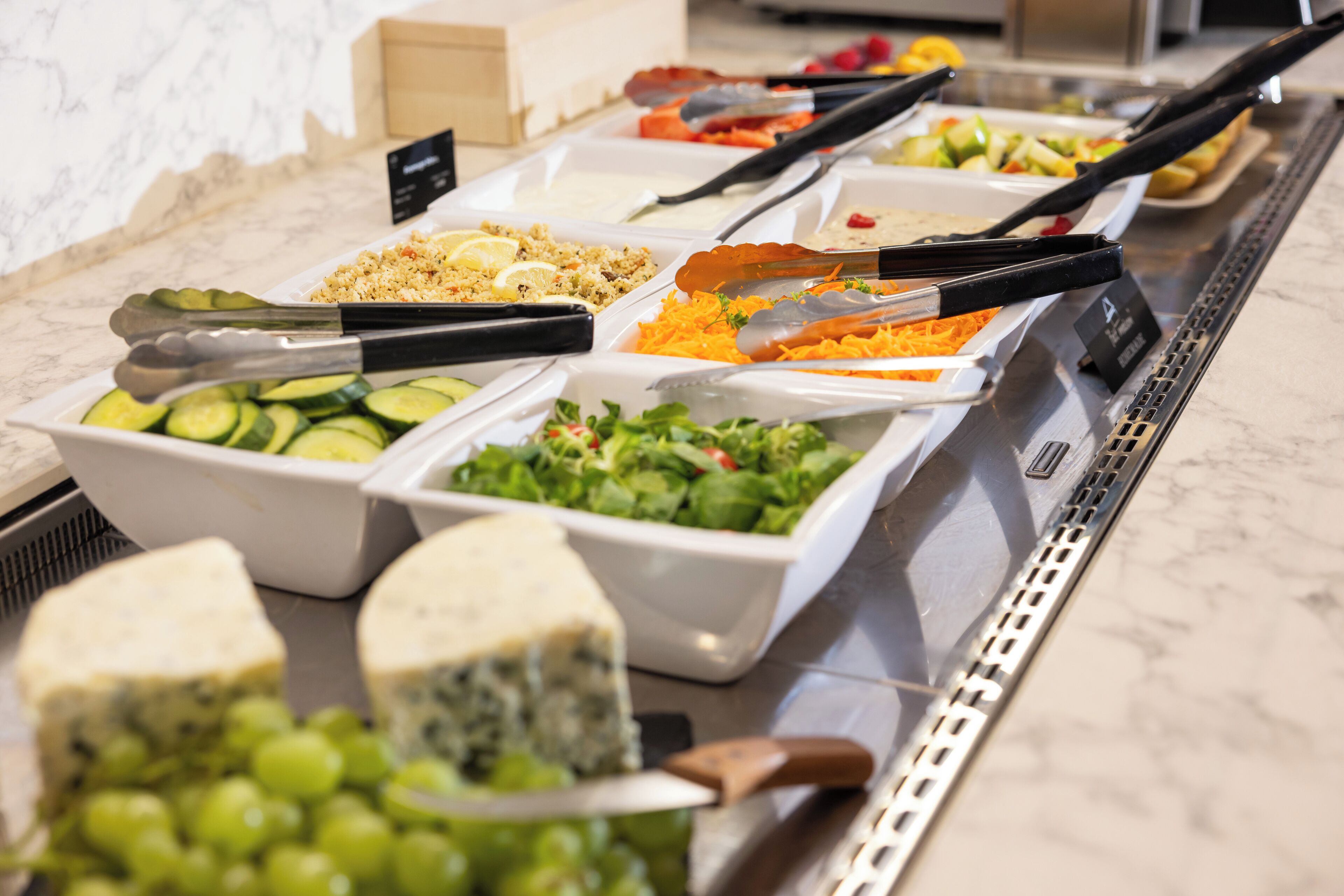 A buffet with various food items including cheese, salads, and fruits.