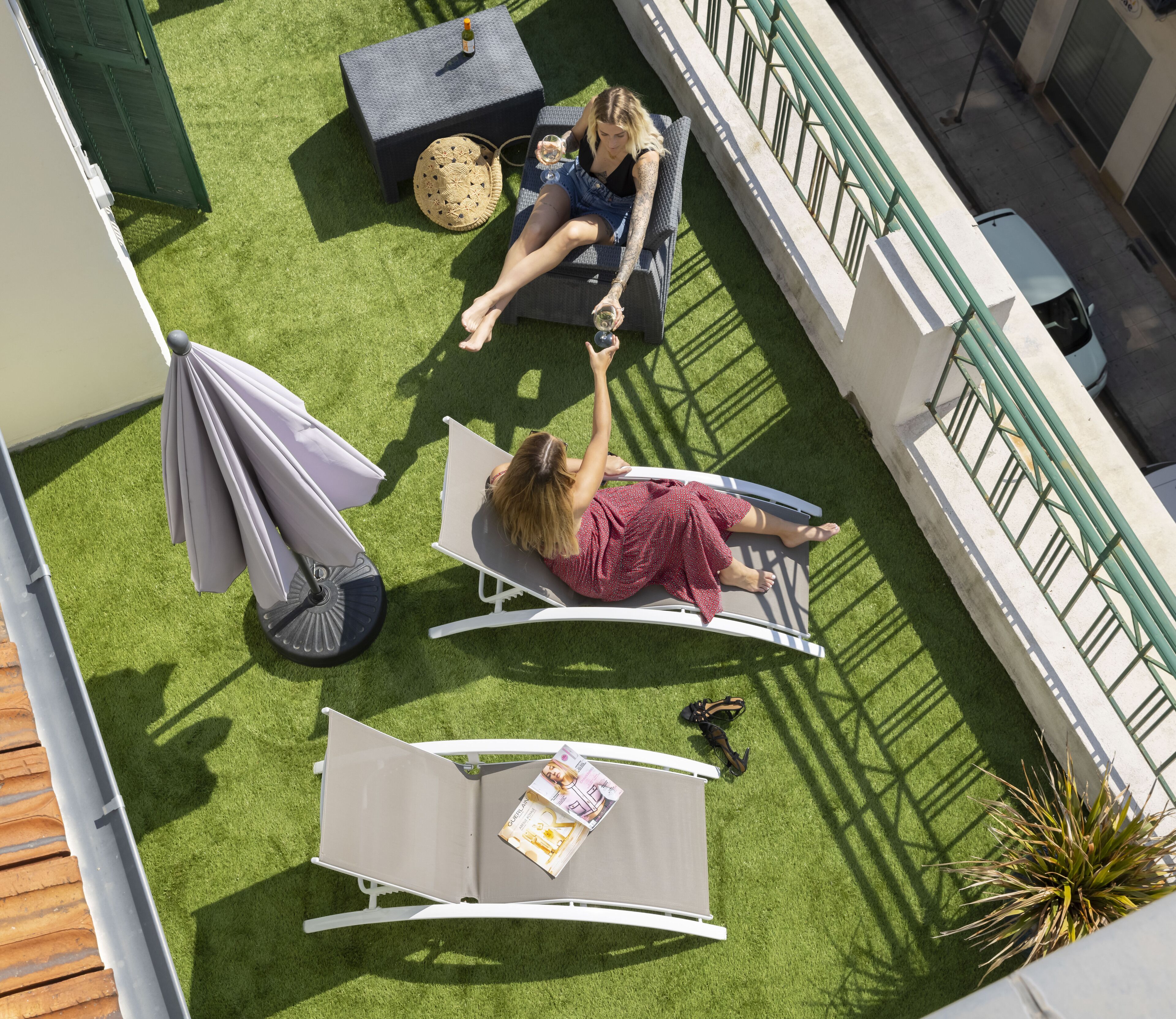 Een terras op het dak met twee lounge stoelen, een bijzettafeltje met een fles, en een gevlochten mand.