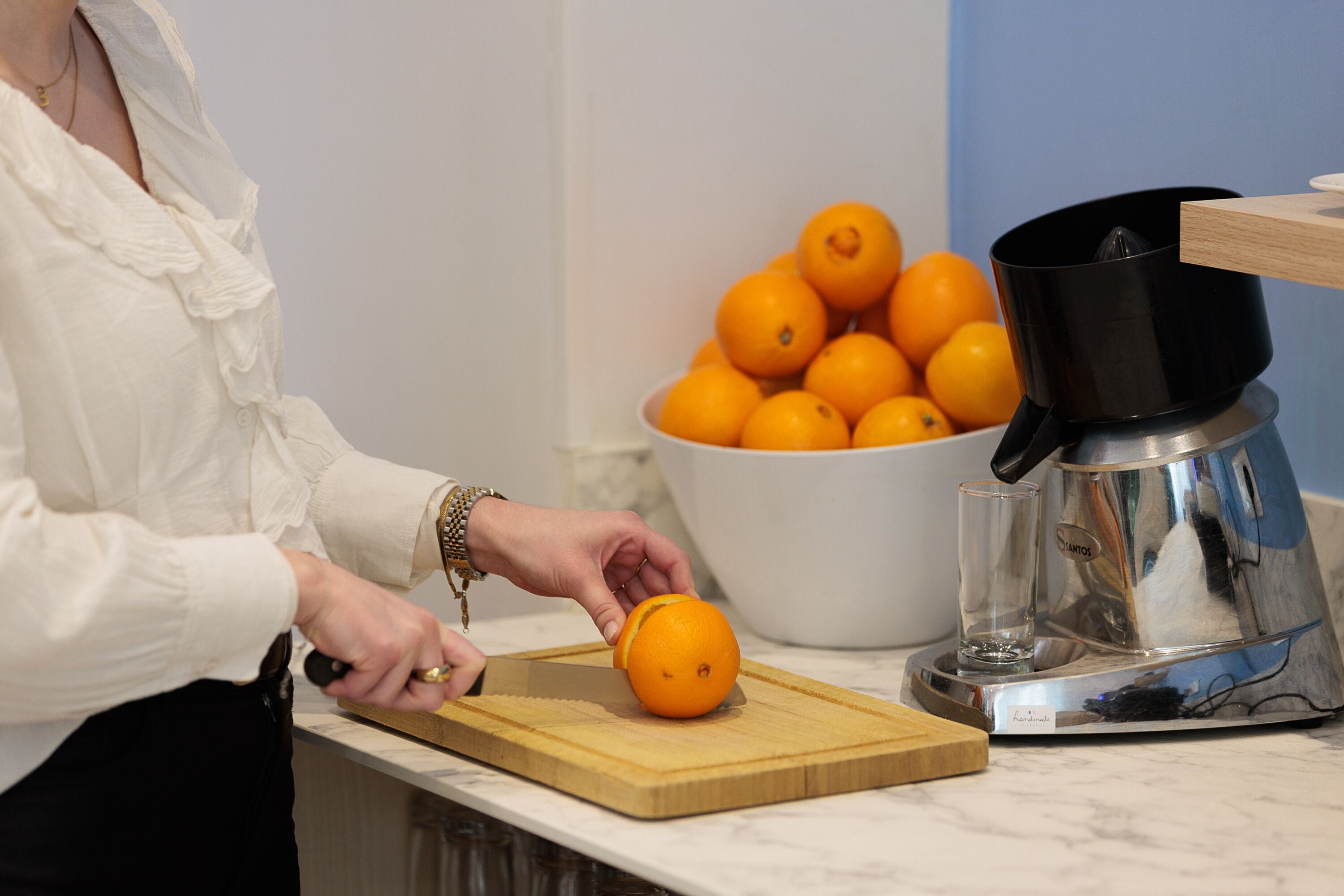 A person preparing oranges on a cutting board with a juicer nearby.