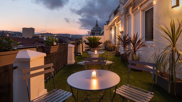 Une terrasse extérieure avec une table et des chaises, un banc et une bougie.