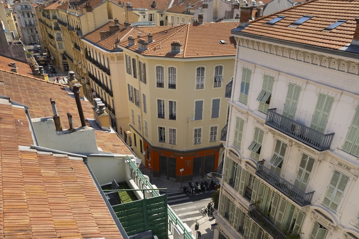 Une terrasse sur le toit avec une pelouse verdoyante, des sièges extérieurs et une vue sur les bâtiments environnants.