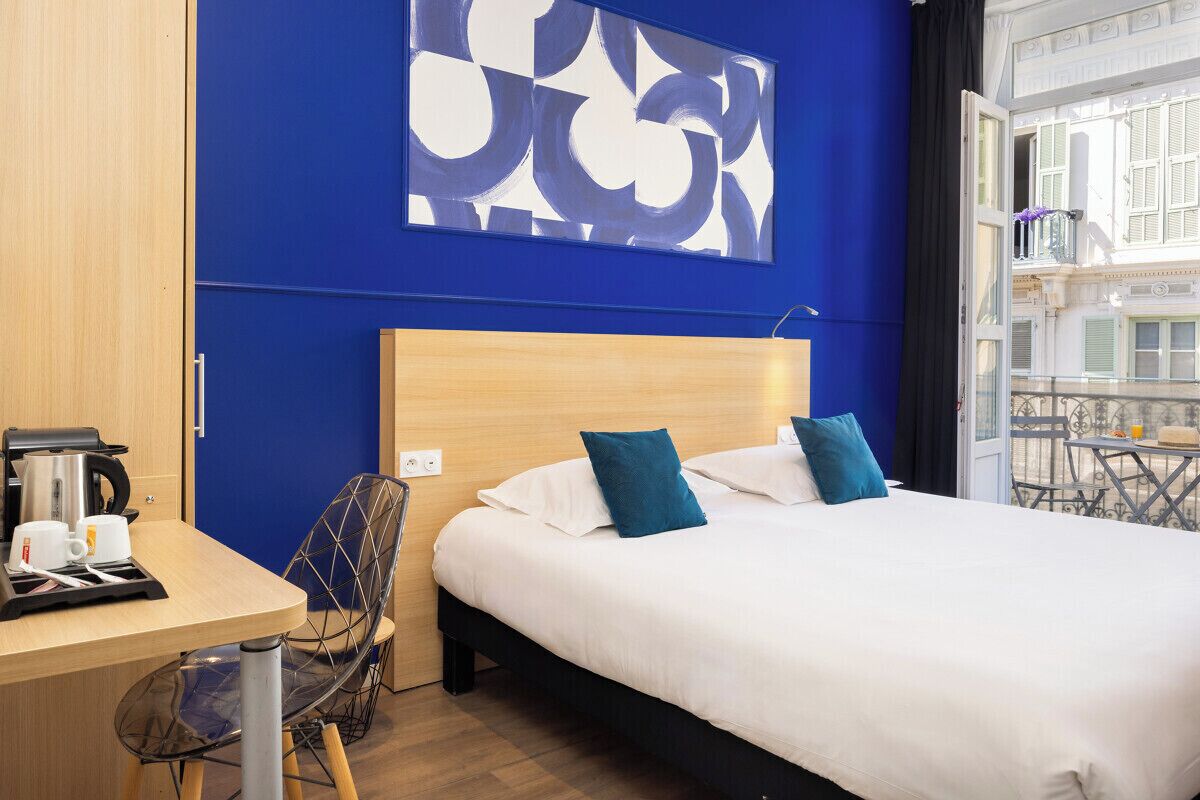 Una habitación de hotel con una cama, un escritorio con cafetera y una silla.