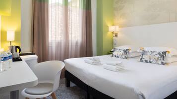 Une chambre d’hôtel comprenant un lit, un bureau avec une chaise, une lampe et un téléphone.
