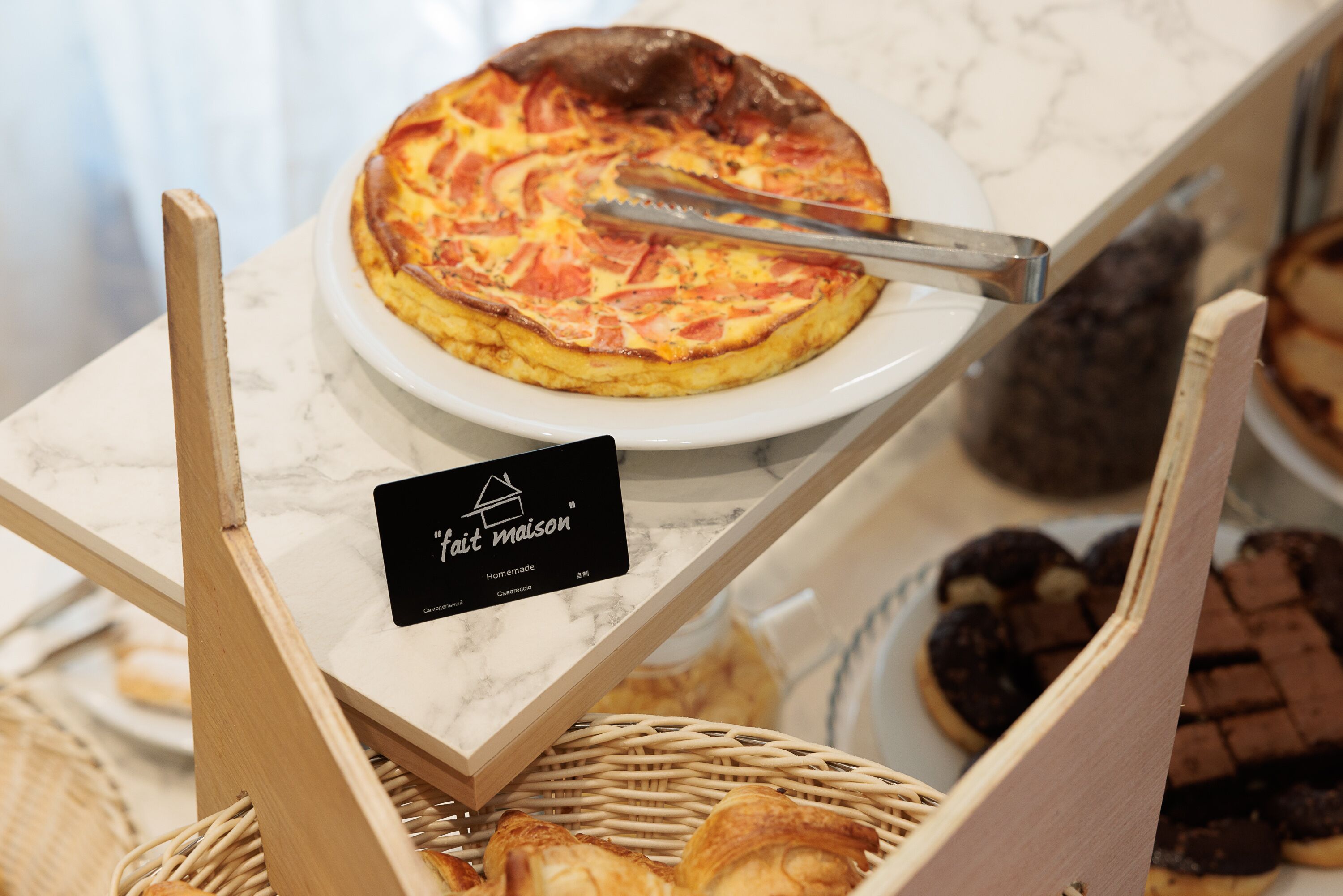 Una exhibición de productos horneados, como una quiche y pasteles, sobre una encimera de mármol.