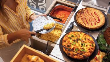 Un buffet proposant divers plats, notamment des œufs brouillés, une tarte et une pizza.