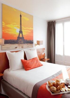 A hotel room with a bed, pillows, a painting of the Eiffel Tower, a nightstand, a window with curtains, and a breakfast tray. - Hôtel Alyss Cambronne Eiffel (Paris)