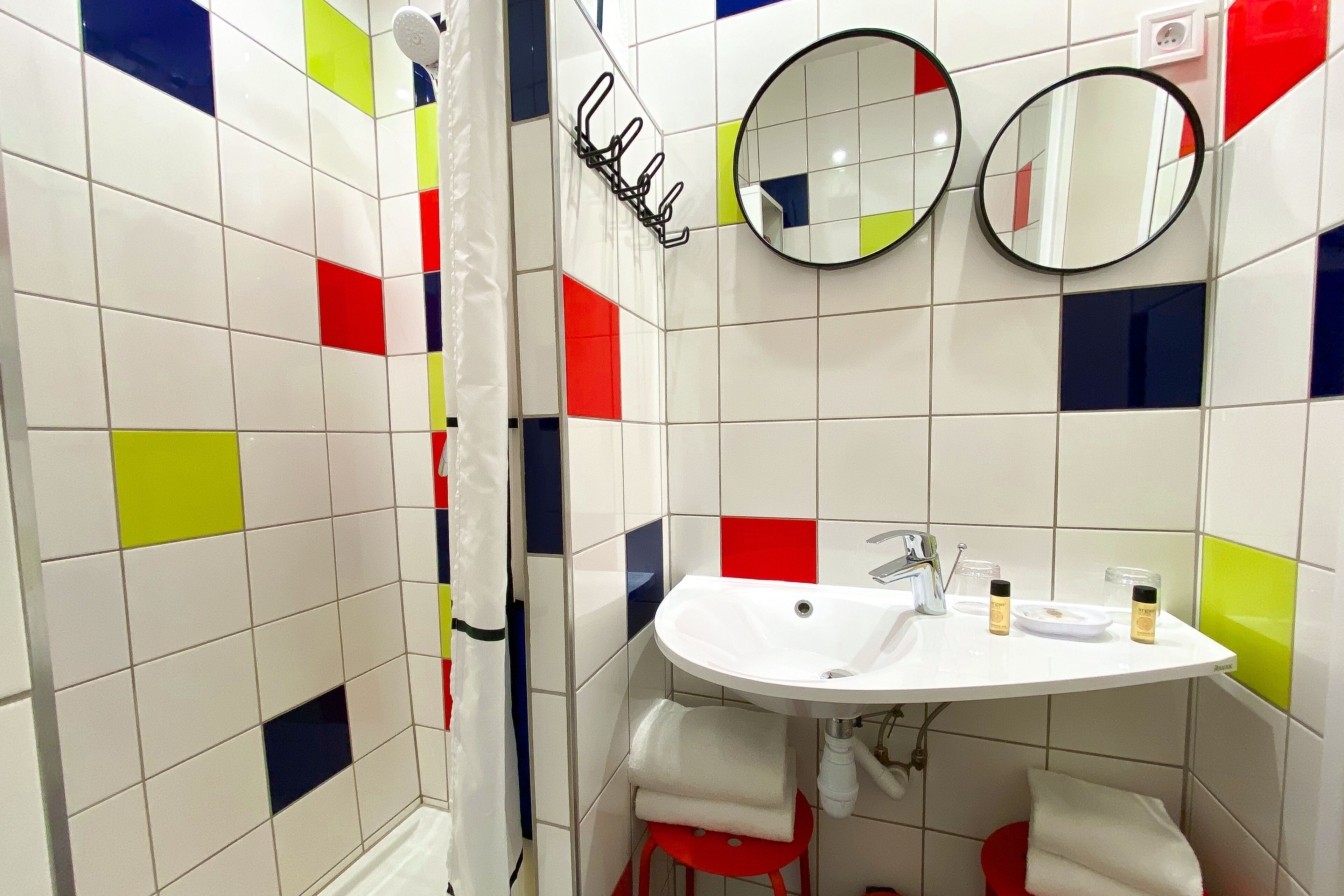 Ein Badezimmer mit einem weißen Waschbecken, zwei Spiegeln und einer Duschvorhang.