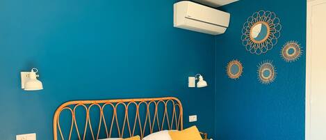 A bedroom with a blue wall, a wooden bed frame, and a white bedspread.