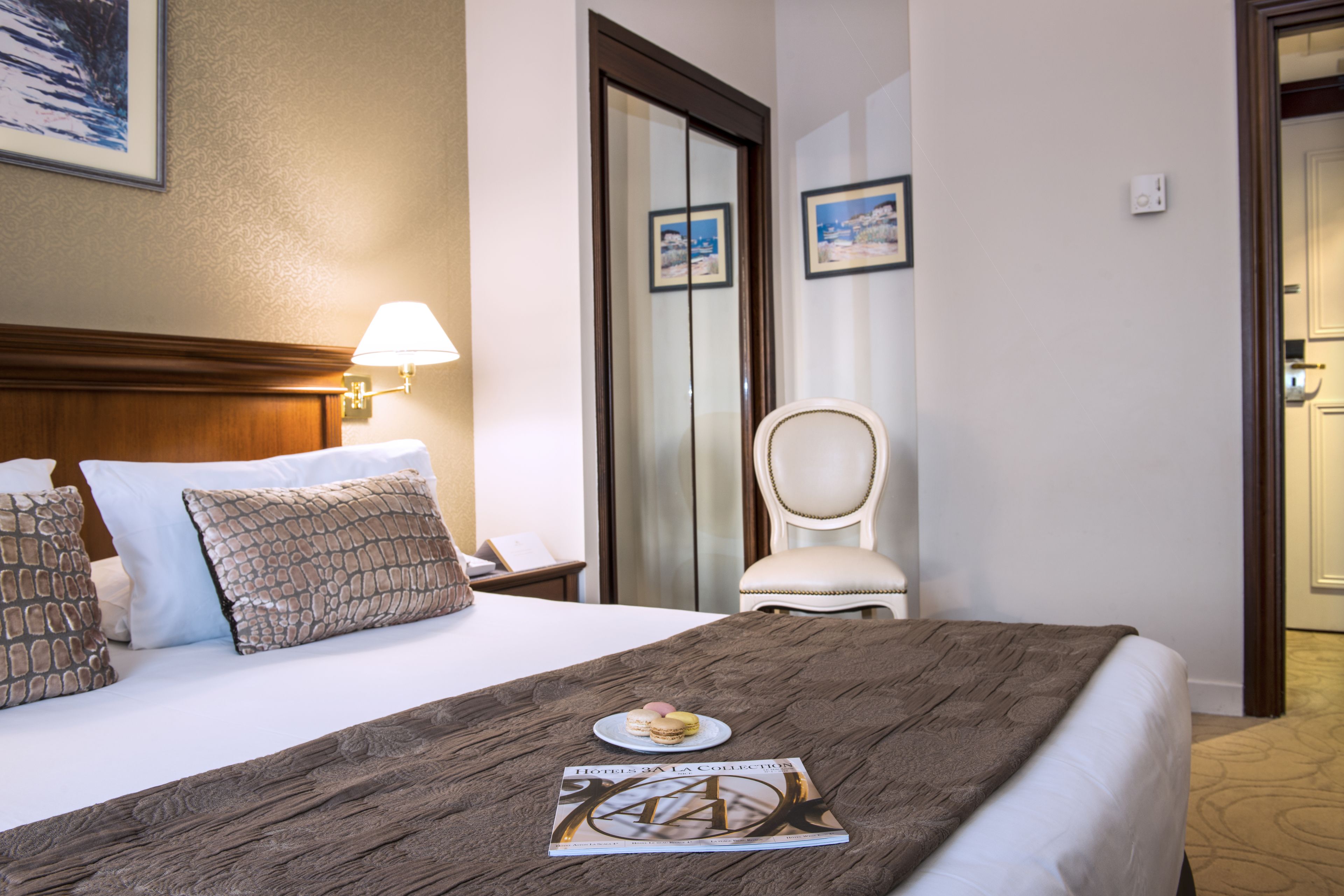 A hotel room with a bed, a nightstand, a lamp, a chair, and a door.