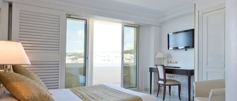 Habitación de hotel con una cama grande, un escritorio, una silla, televisión y vistas a la ciudad.