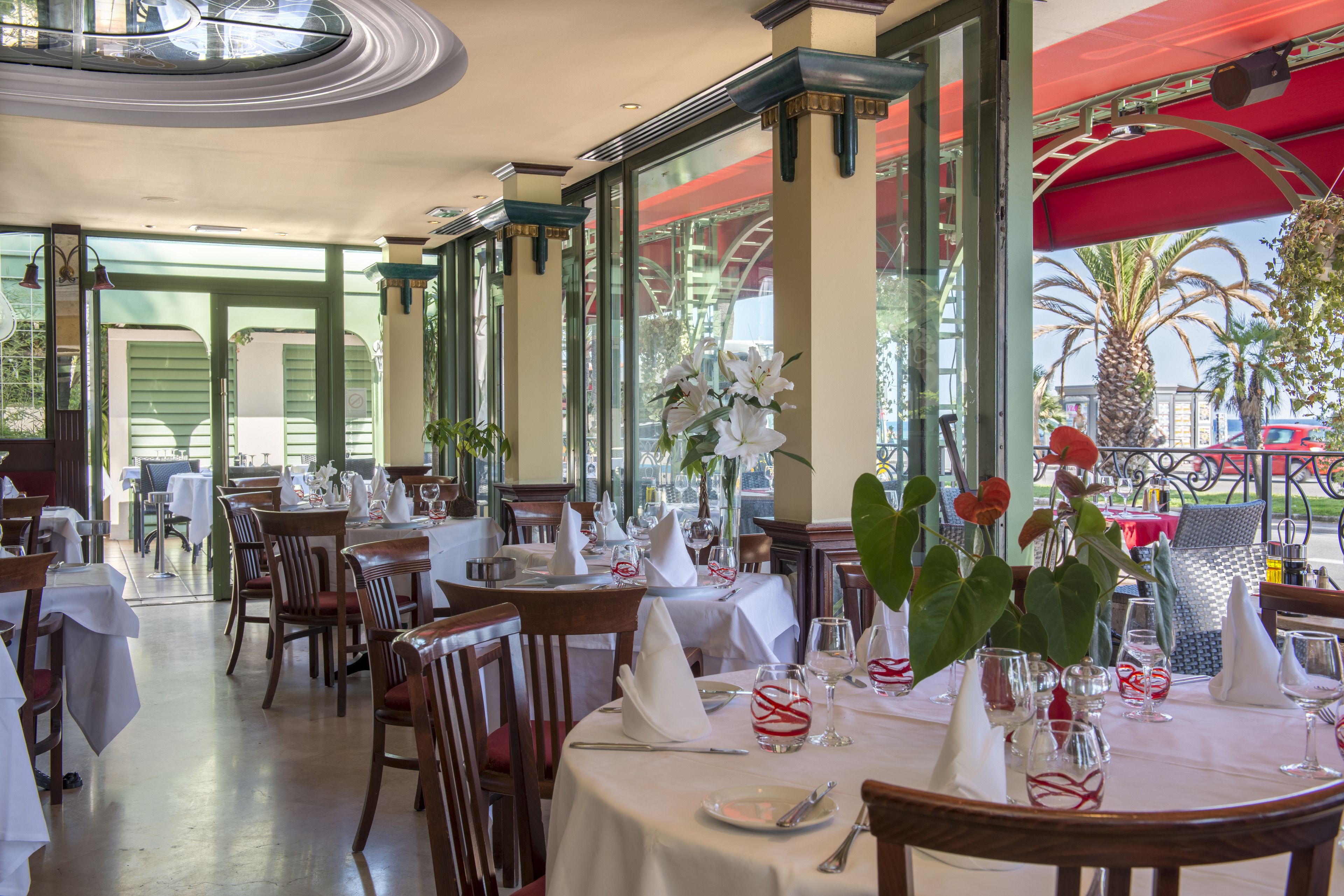 Un restaurante con mesas dispuestas para comer, con manteles blancos, sillas y cubertería ordenada.
