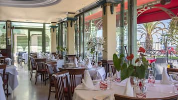 Un restaurante con mesas dispuestas para comer, con manteles blancos, sillas y cubertería ordenada.