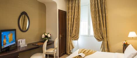 A hotel room with a bed, a desk with a chair, a television, and curtains.