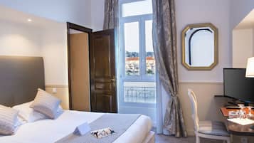 Una habitación de hotel con una cama, un escritorio con silla, televisión y ventana con cortinas.