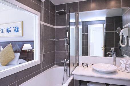 A modern bathroom with a bathtub, a large mirror, and a vanity with a sink.