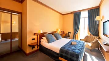 Ein Hotelzimmer mit einem großen Bett, einem Schreibtisch, einem Stuhl und einem Fernseher.