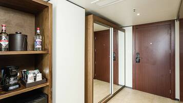 A hotel room with a minibar, a coffee machine, and a mirror.