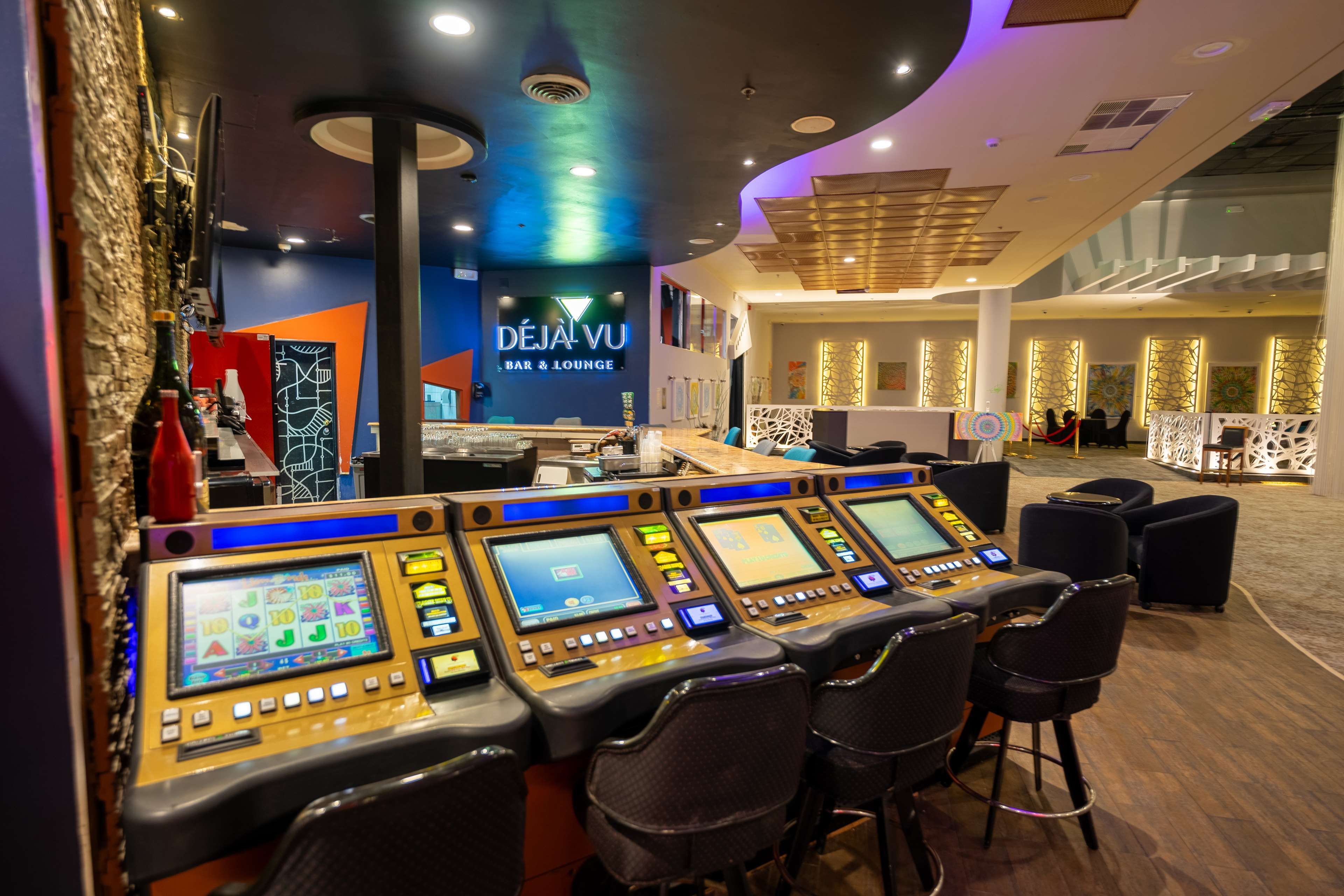 A control panel with multiple screens and buttons, a bar area with a counter, and a lounge area with chairs.