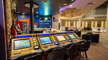 A control panel with multiple screens and buttons, a bar area with a counter, and a lounge area with chairs.