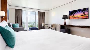 Une chambre d’hôtel moderne dotée d’un grand lit, d’un bureau, d’une chaise et offrant une vue sur la ville grâce à de grandes fenêtres.