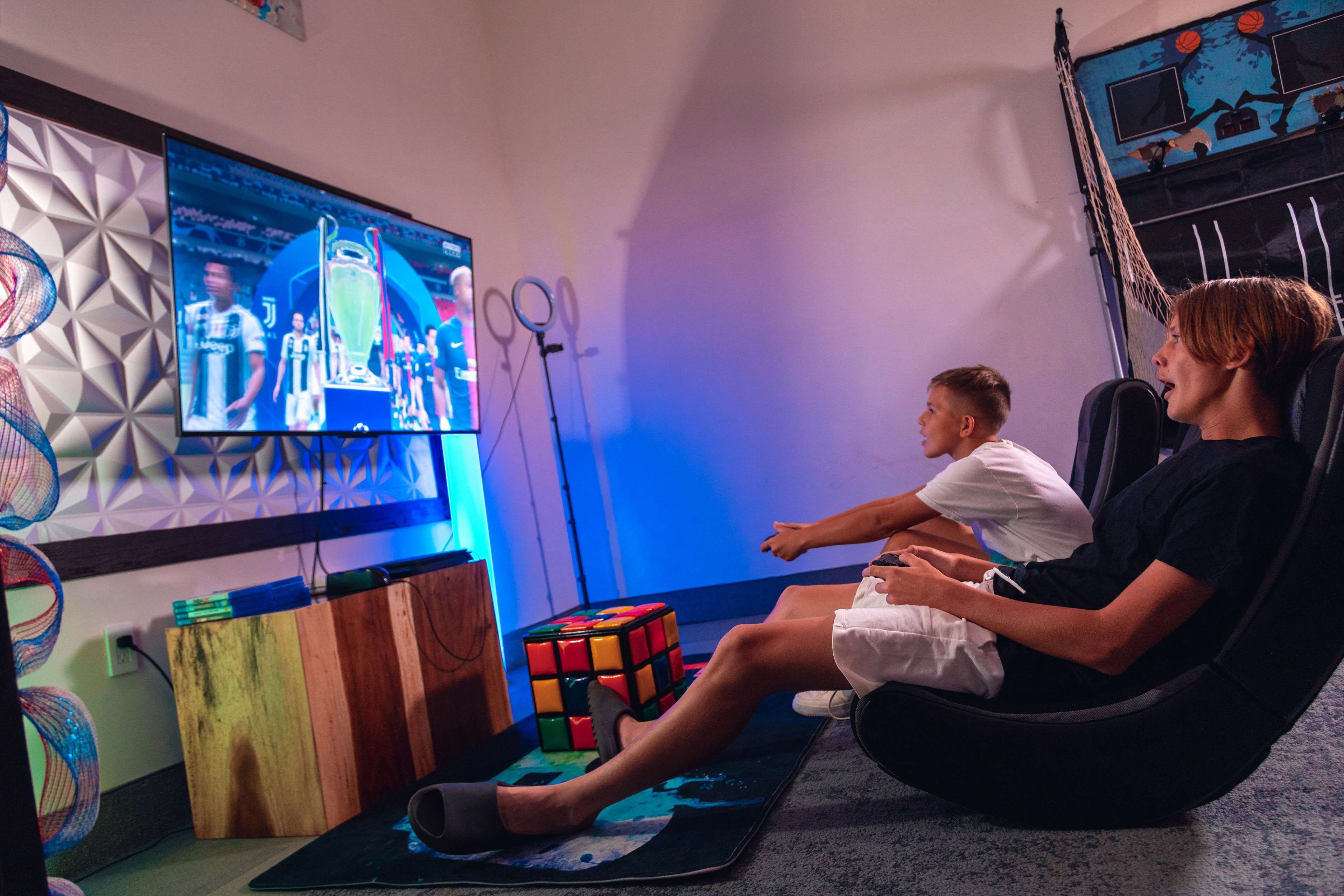 Two people seated on a couch watching a TV screen.