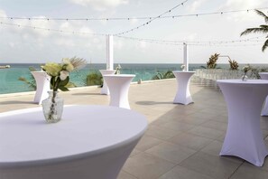 An outdoor terrace with round tables, white tablecloths, and string lights. - Sonesta Maho Beach All Inclusive Resort Casino & Spa (Lowlands)