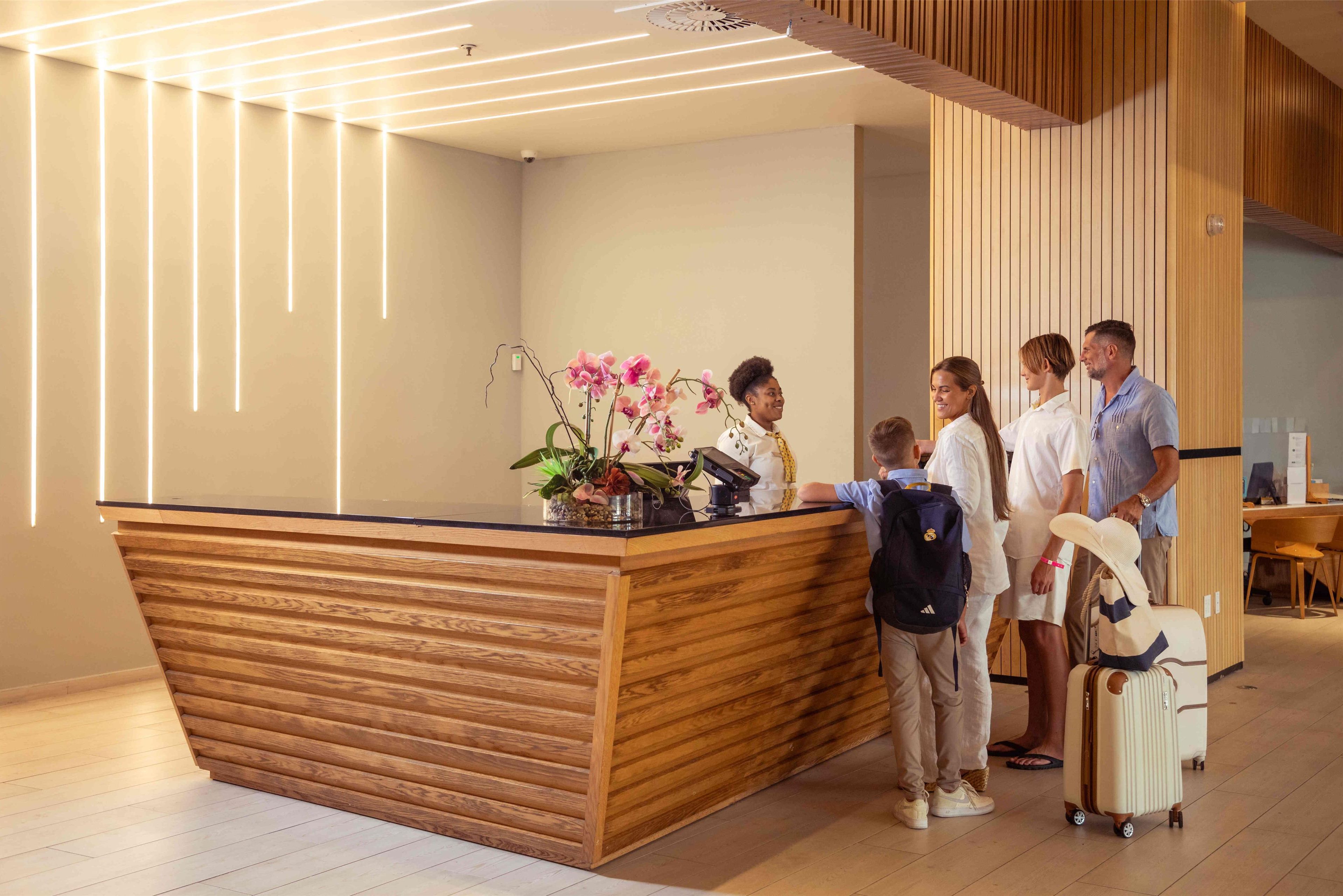A reception desk with a wooden finish and a vase of pink flowers.
