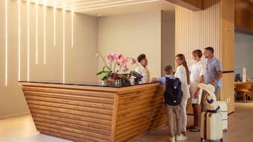 A reception desk with a wooden finish and a vase of pink flowers.