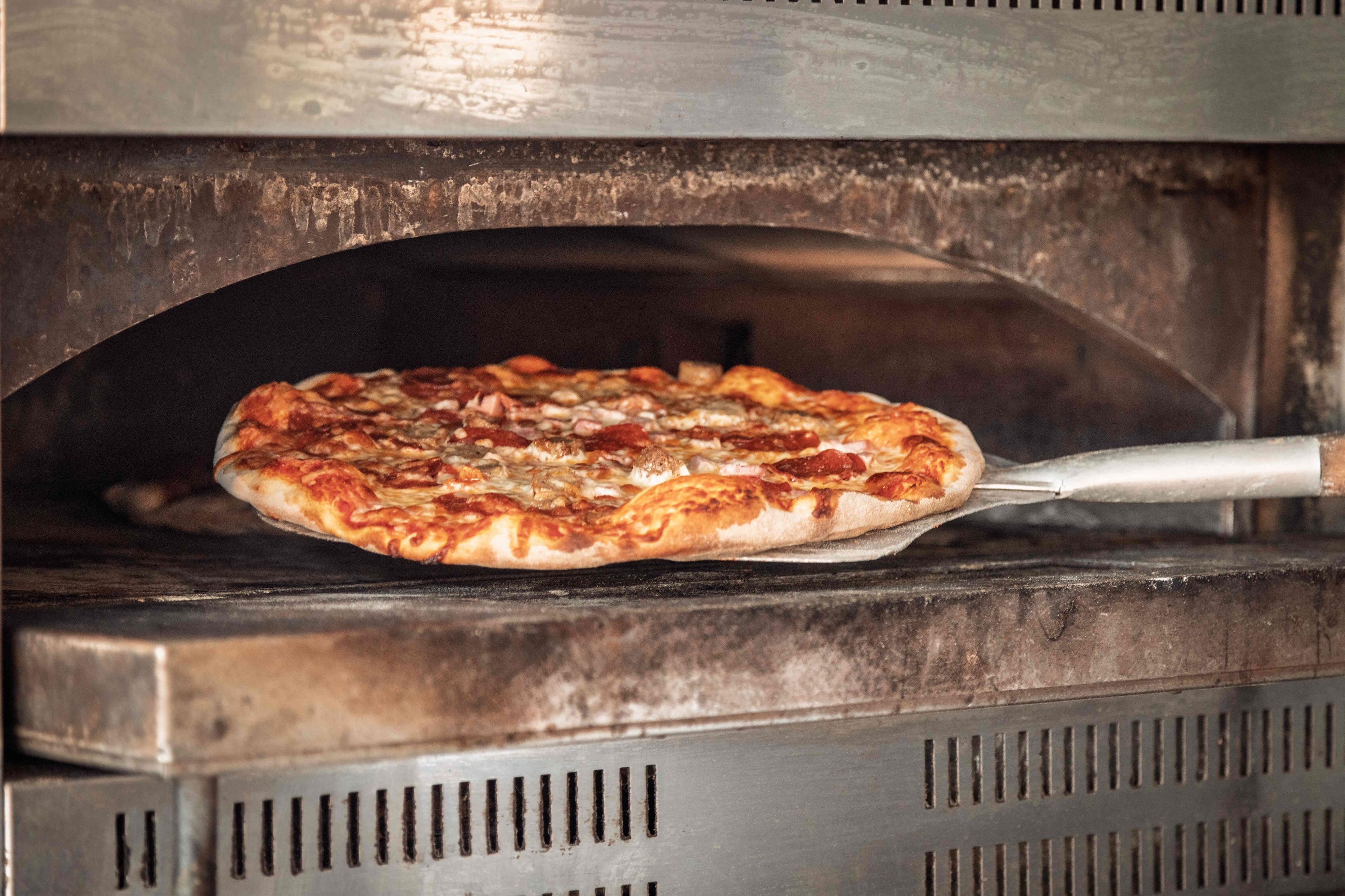 A pizza being removed from an oven.