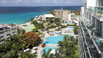 A resort with a large pool, palm trees, and a view of the ocean.