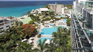 Un resort con una piscina amplia, palmeras y vista al océano.