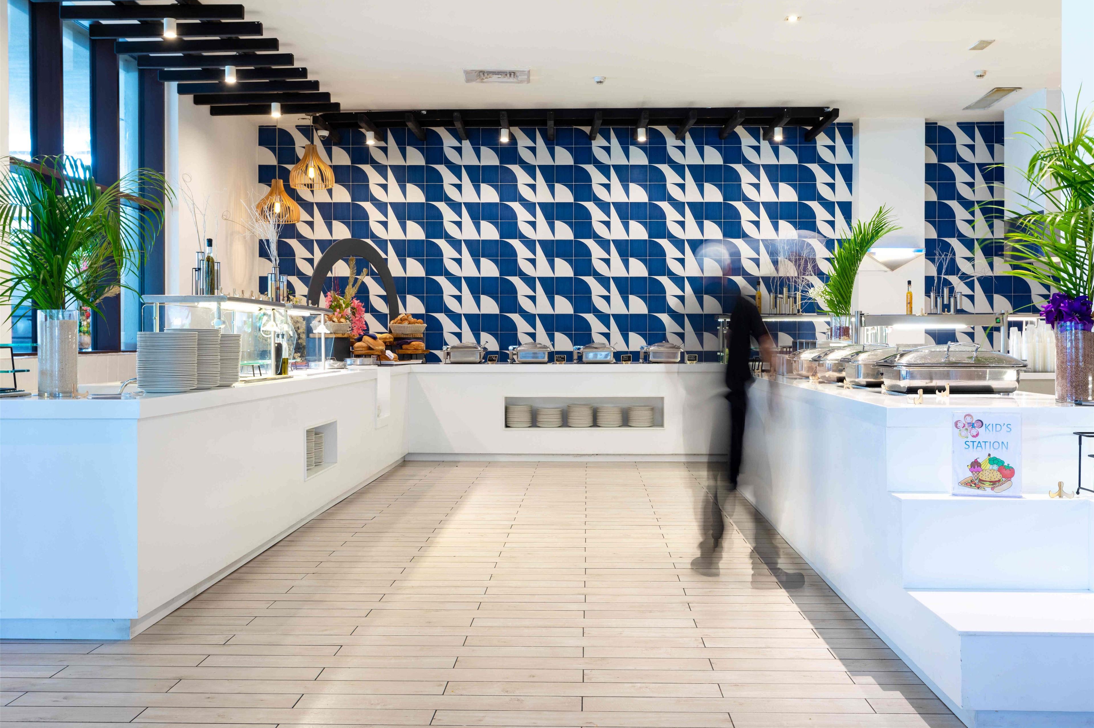 Un espace d’accueil moderne avec un mur aux motifs bleus et blancs, un plancher en bois et un comptoir où sont exposés divers objets.
