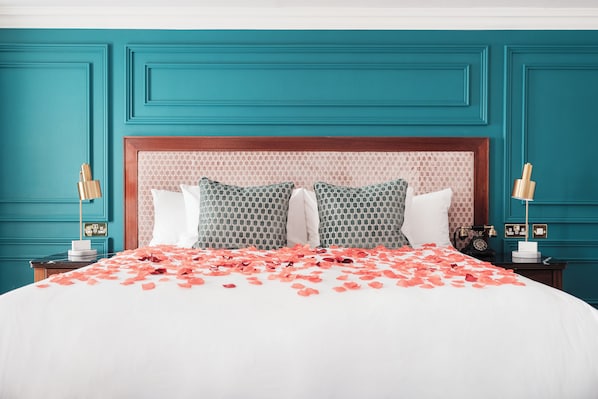 Una cama con una colcha blanca y paredes color turquesa.