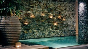 A stone wall with embedded lights, a pool, and a large potted plant. - Imperial Hotel (Cork)