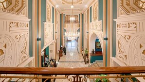 A grand hallway with ornate wall decorations, a chandelier, and a marble floor. - Imperial Hotel (Cork)