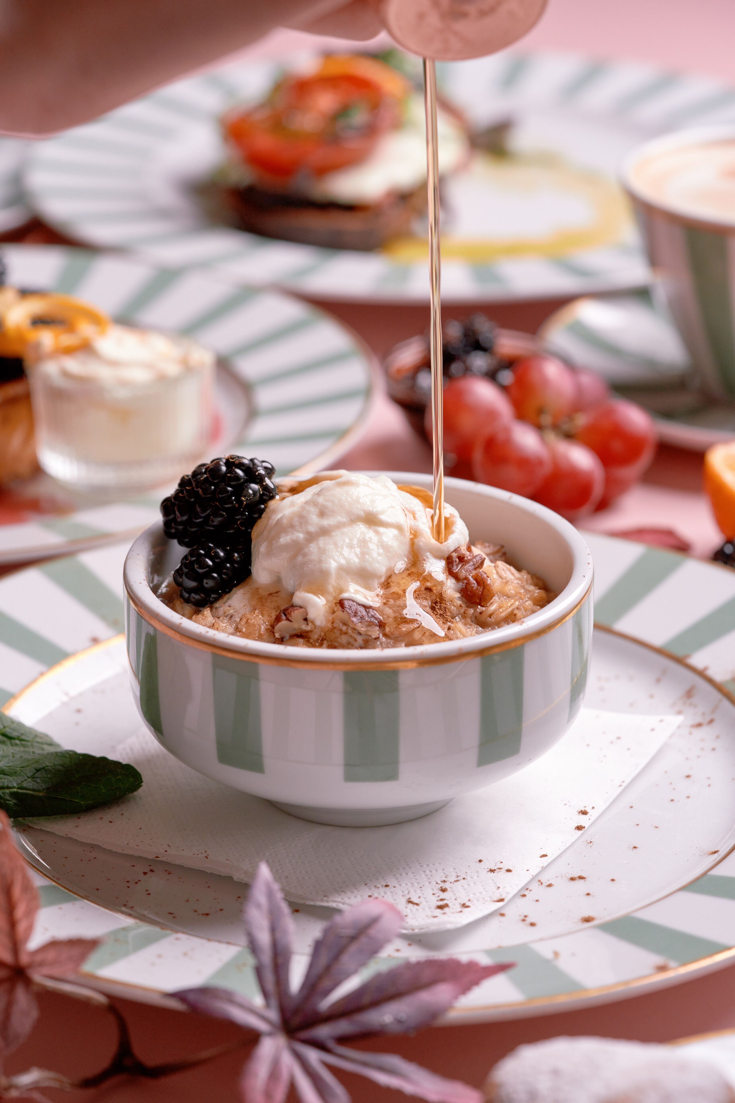 Un bol de dessert avec une boule de glace et une mûre sur le dessus, et une cuillère qui verse du sirop à l'intérieur.