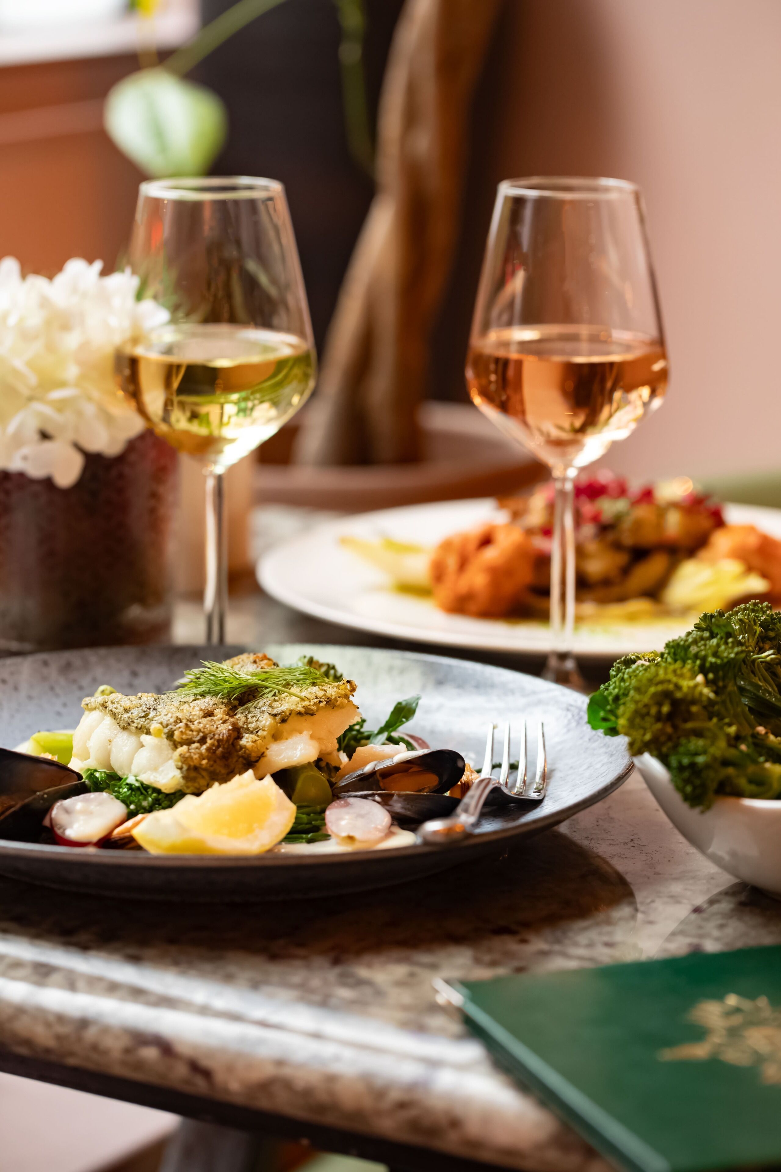 Ein Esstisch mit Fischplatten und einem Glas Weißwein.