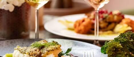 Ein Esstisch mit Fischplatten und einem Glas Weißwein.