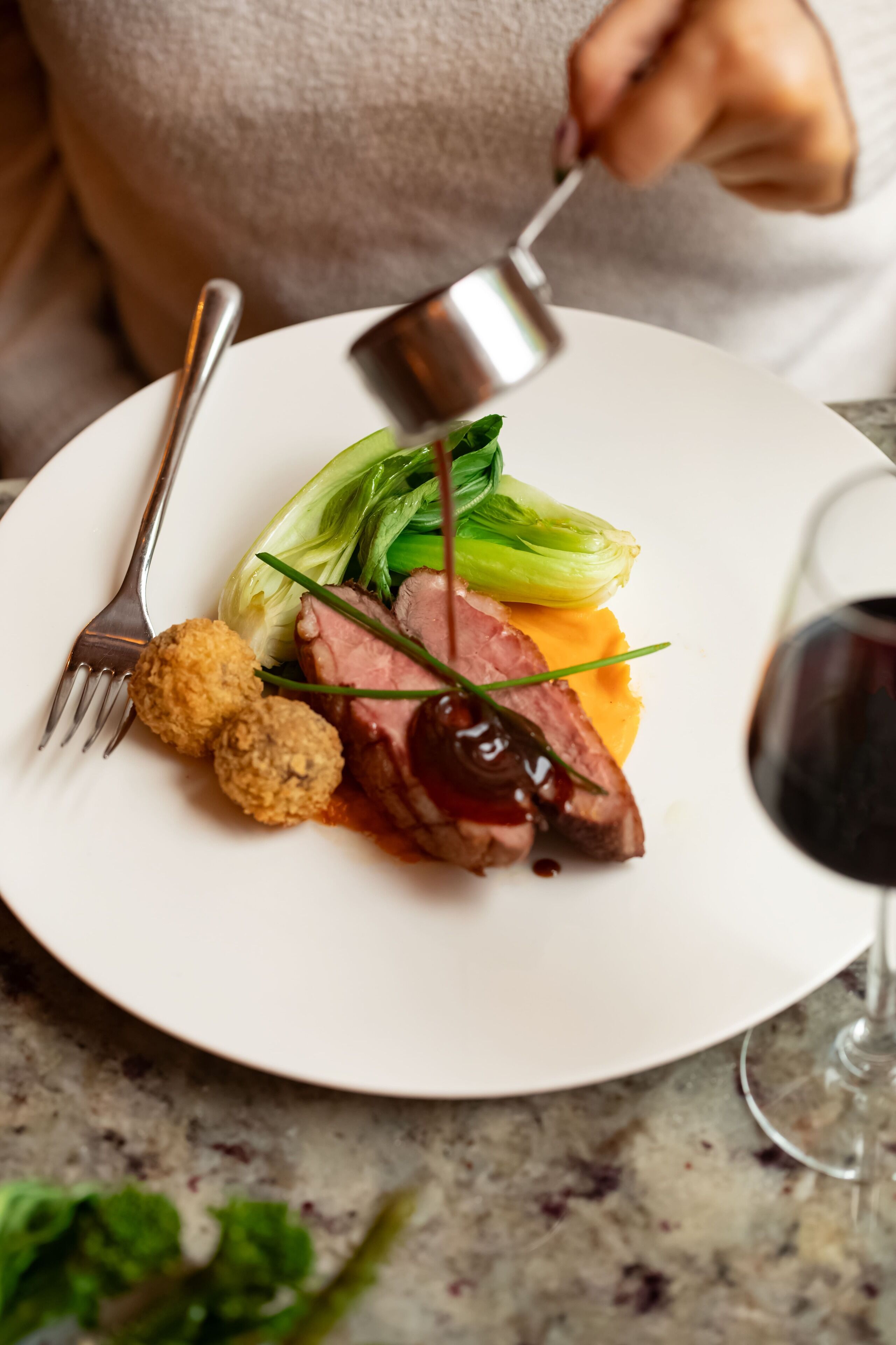 Un plato de comida con un tenedor y una copa de vino tinto.