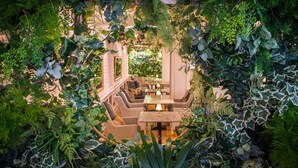 An indoor garden with a central seating area, surrounded by lush greenery and plants. - Imperial Hotel (Cork)