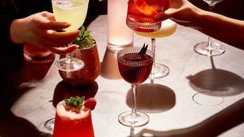 A table with various drinks, including cocktails and a non-alcoholic beverage, with a person holding a glass.