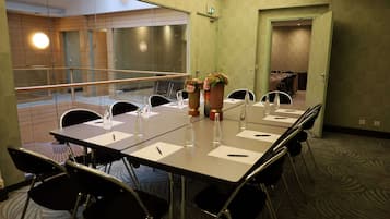 A conference room with a long table, chairs, and water bottles. There are two vases with flowers on the table.