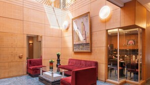 A lobby with a modern design, featuring red seating, a glass coffee table, and a painting on the wall. - Le patio Bastille (Paris)