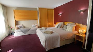 A hotel room with two beds, a wooden headboard, a red accent wall, and a nightstand with a lamp.